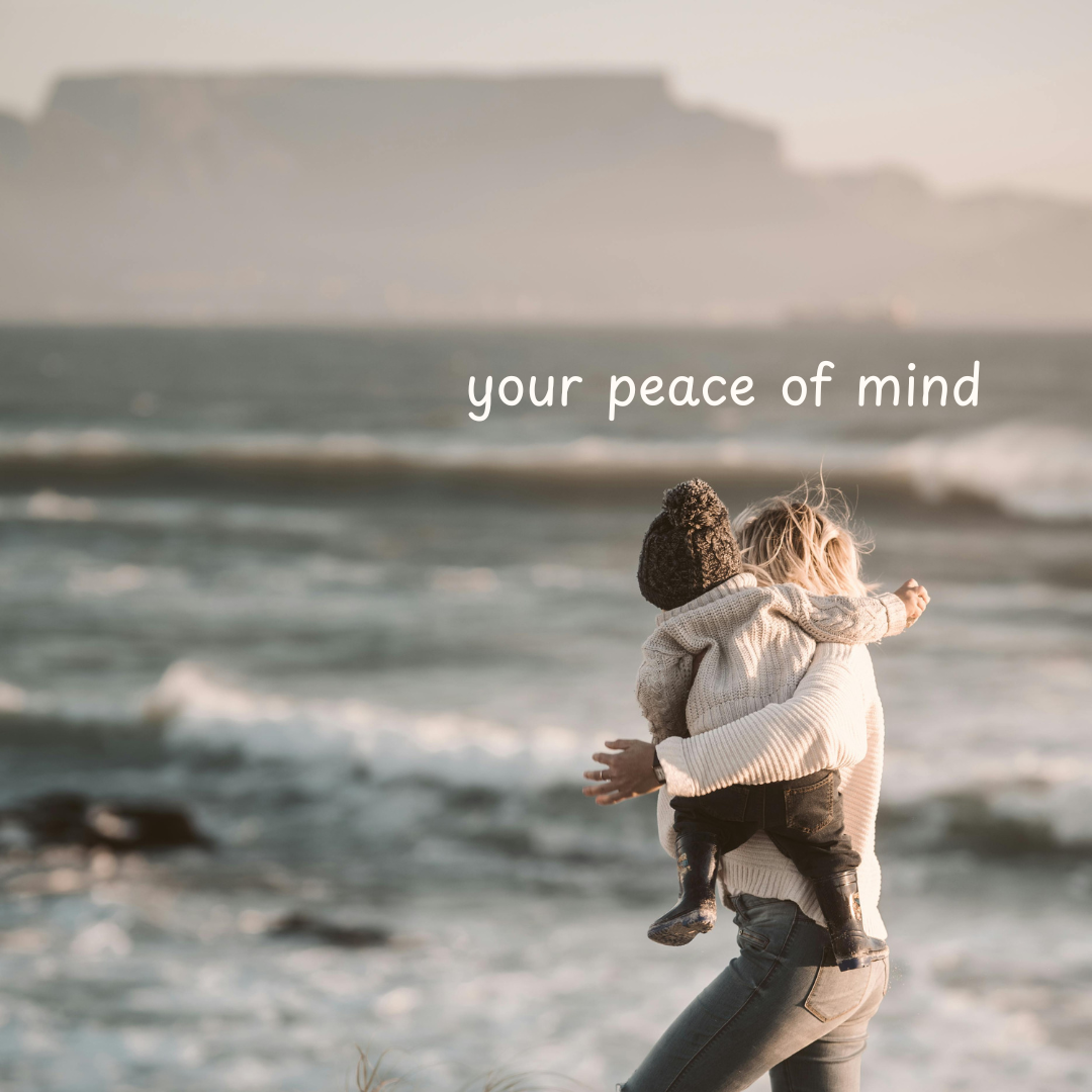 A mother holding her young son with the ocean and Table Mountain in the background. There is white text that says, "Your peace of mind". 
