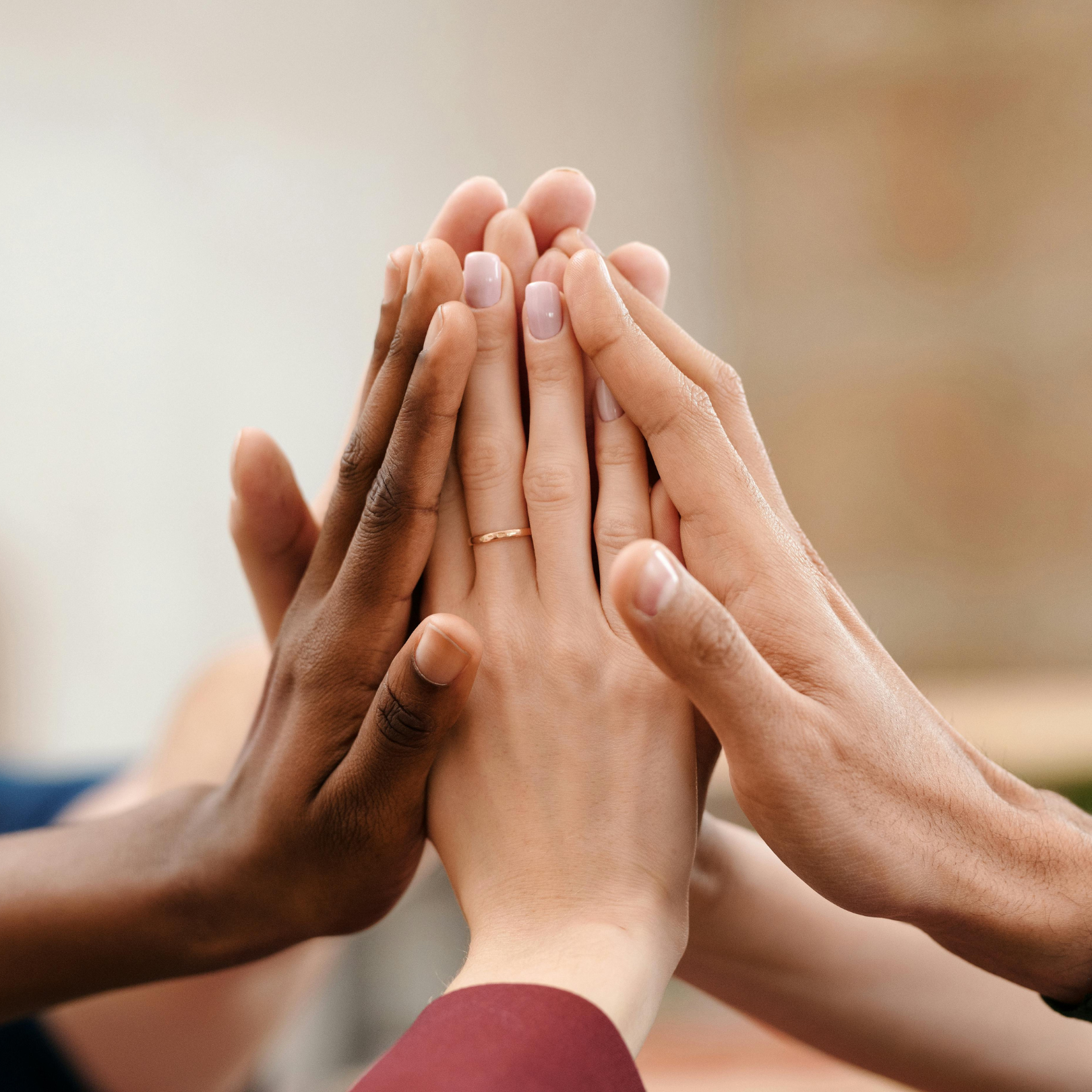 Five hands of different skin tones touch their palms together in a gesture that exudes warmth and unity.